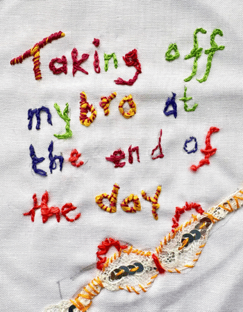 Threads of Freedom Project - stitching onto cloth fabric in different colours which says 'Taking off my bra at the end of the day'